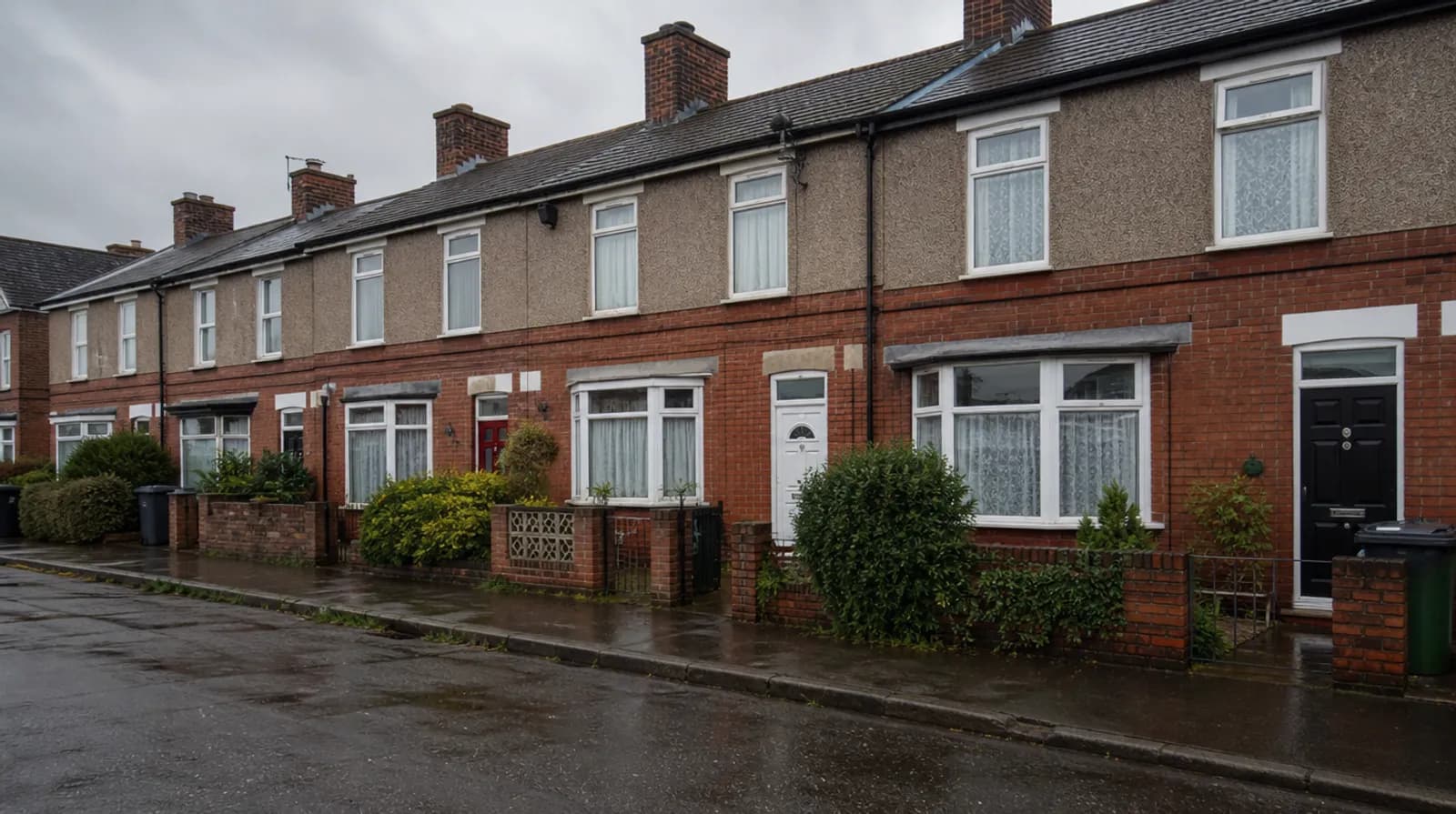A row of British council-built terraced houses on a wet, overcast day
